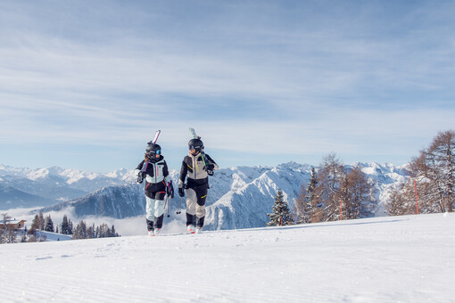Skiers enjoy the sunny winter day on the perfectly groomed slopes of the Rofan mountains, backdropped by the snow-covered Nature Park Karwendel.